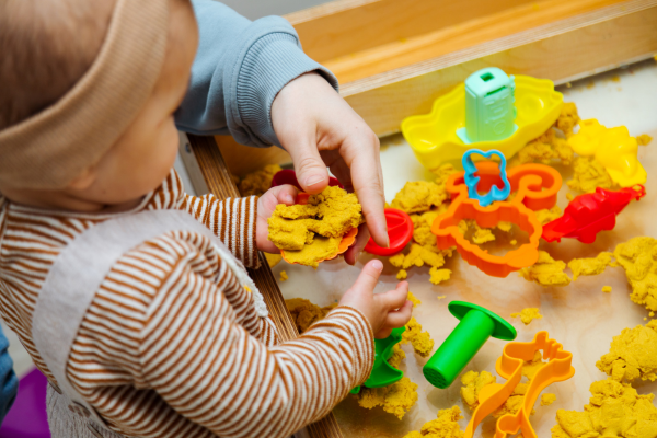 Early Years Educator and baby playing with sand